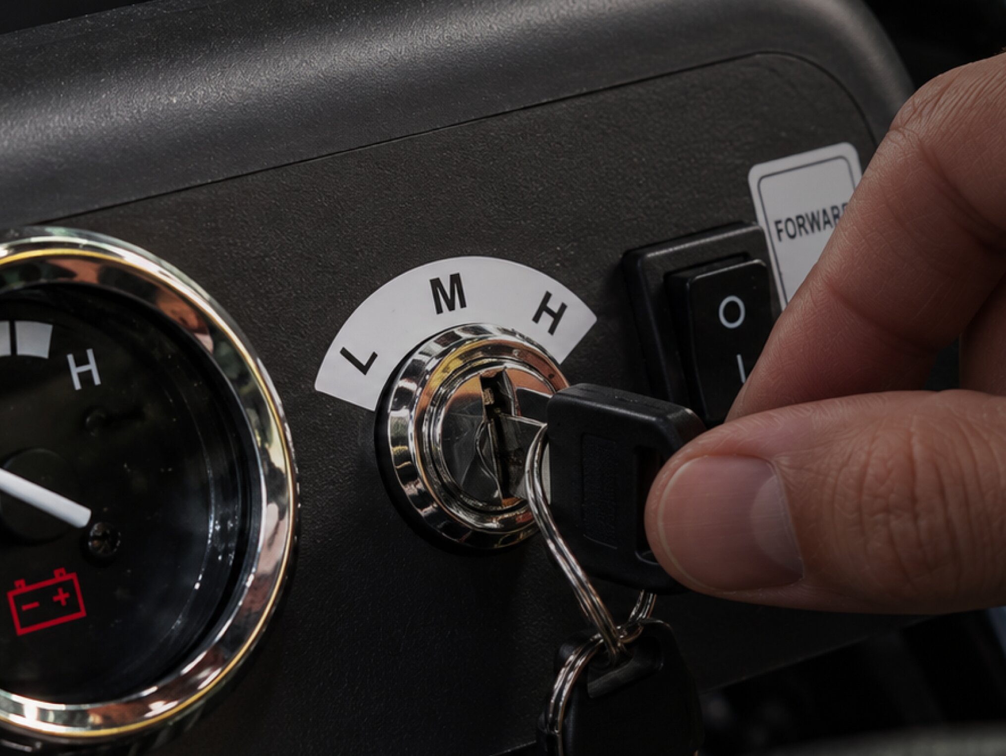 Hand at a go-kart speed selector marked L, M and H