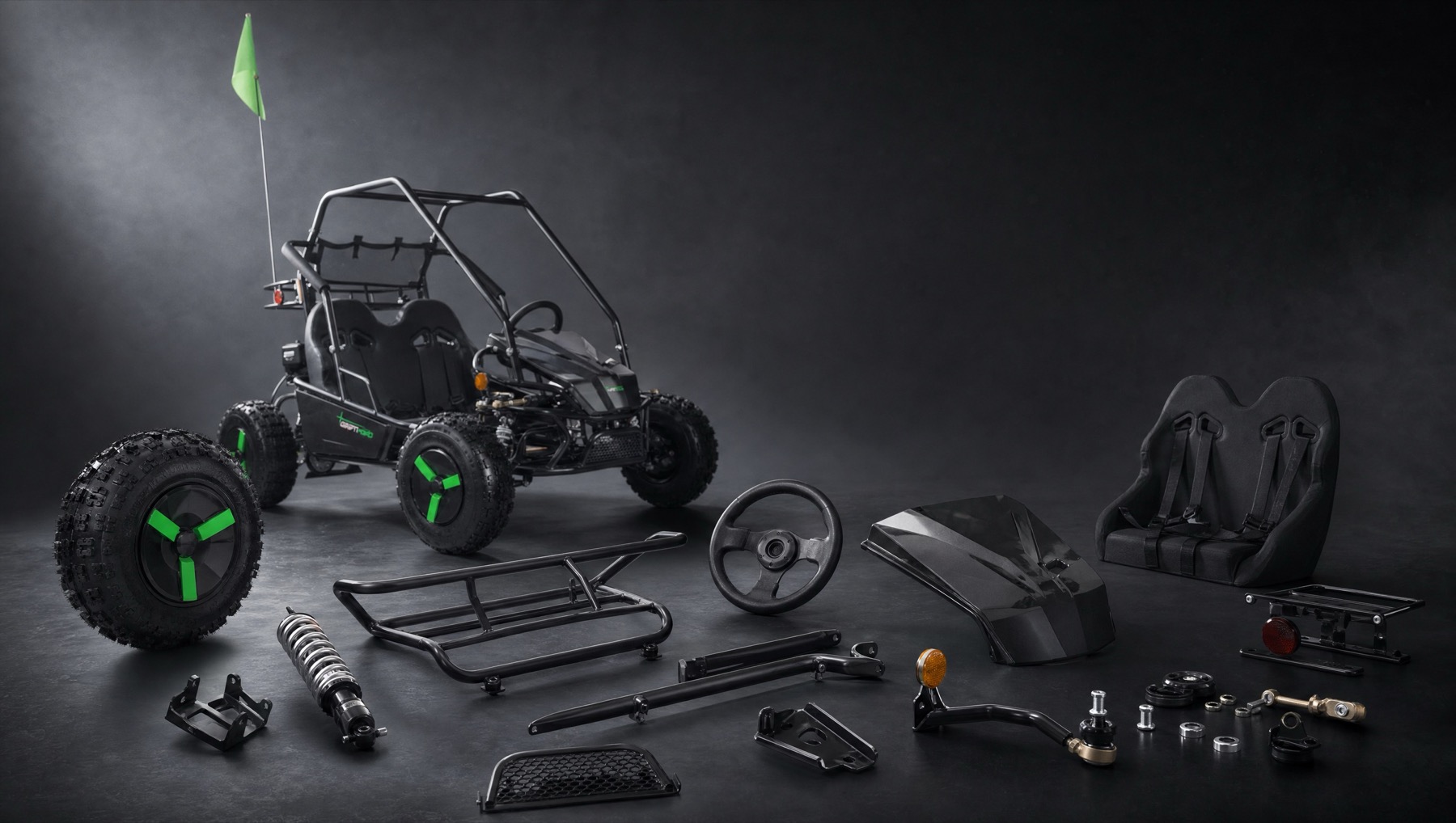 Go-kart replacement parts, wheels and shocks laid out neatly on a dark workshop floor